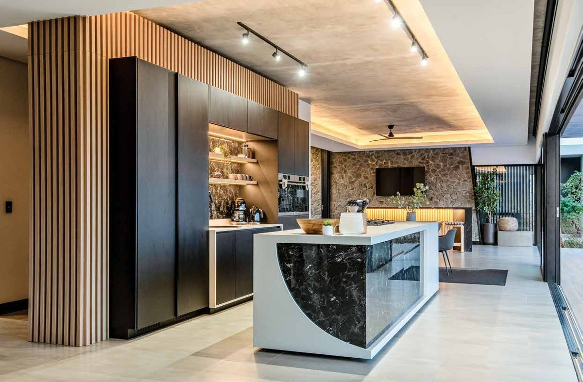 Sculptural kitchen island with warm wood and dark finishes. Photography: Stephen Rowley.